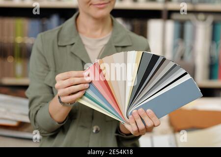Hands of young female manager of studio of interior design showing palette with samples of new leather for furniture against workplace Stock Photo