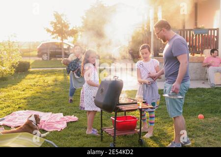 Picture of big happy family making barbeque in their backyard. Family time on sunny summer day. Stock Photo