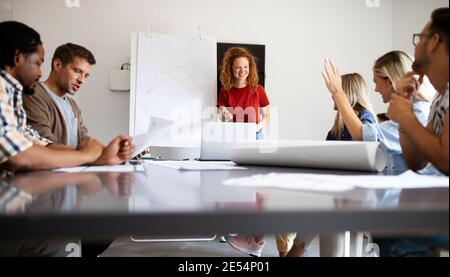 Young architect colleagues are analyzing blueprints while working on a new project Stock Photo