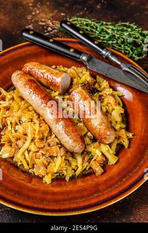 Bigos Stewed cabbage with mushrooms and meat sausages on a plate. Dark background. Top view Stock Photo