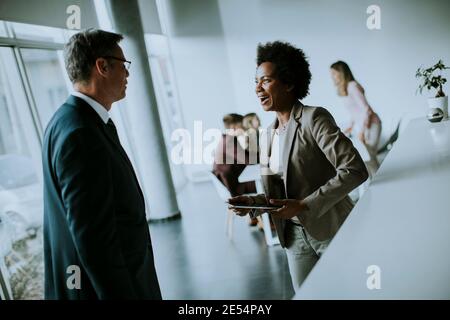 African American businesswoman holding digital tablet and talking with handsome colleague in office Stock Photo