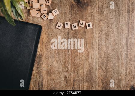 Jesus spelled in block letters on a wooden table with a bible and a plant Stock Photo