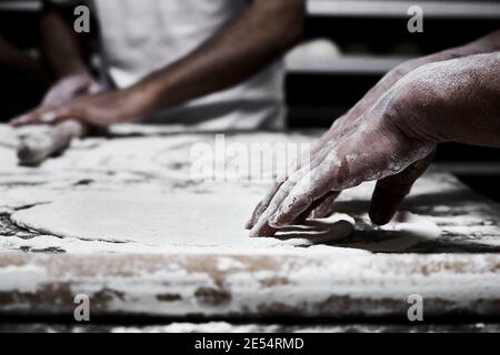 Hands of pastry chef and baker while kneading the pizza dough Stock Photo