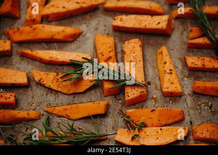tray of oven baked sweet potato chips in closeup. Baked with paprika, rosemary and salt. Homemade cooked sweet potatoes with spices and herbs on oven- Stock Photo