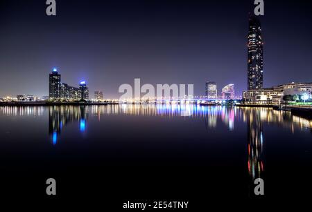 Beautiful night view of illuminated business bay bridge across the water with reflections surrounded by the majestic sky scrapers captured in Dubai