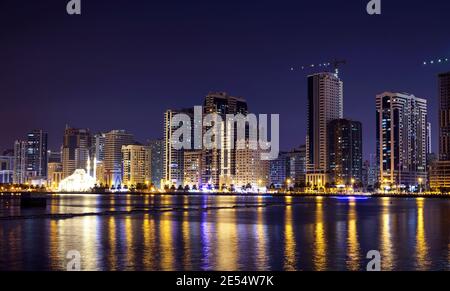 Panaromic view of the illuminated sky scrappers along with Al Noor mosque with reflections in water captured at the Al Majaz Waterfront Sharjah Stock Photo