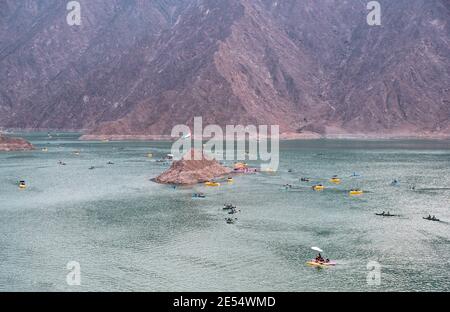 BEAUTIFUL AERIAL VIEW OF THE PADDLE BOATS, KAYAKS IN THE HATTA WATER DAM ON A CLOUDY DAY AT SUNSET TIME IN THE MOUNTAINS ENCLAVE REGION OF DUBAI Stock Photo