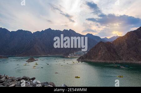 BEAUTIFUL AERIAL VIEW OF THE PADDLE BOATS, KAYAKS IN THE HATTA WATER DAM ON A CLOUDY DAY AT SUNSET TIME IN THE MOUNTAINS ENCLAVE REGION OF DUBAI Stock Photo