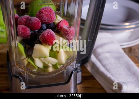 Blender with fresh and frozen cut fruits Stock Photo