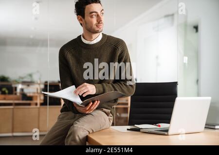 Confident young manager working at the office, holding documents Stock Photo
