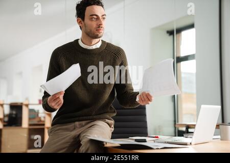Confident young manager working at the office, holding documents Stock Photo