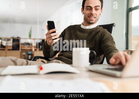 Excited businessman using cell phone at the office desk Stock Photo