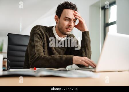 Stressed business man looking at laptop while sitting at the office desk Stock Photo