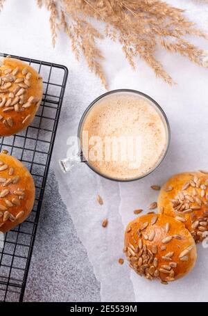Coffee and fresh homemade bread rolls with seeds on cooling rack. Breakfast with coffee and pastries. Top view - Image Stock Photo