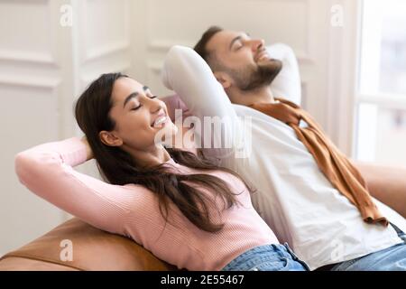 Happy Young Couple Relaxing Sitting On Sofa At Home Stock Photo