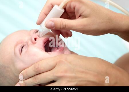 Mother using child's nasal aspirator for baby boy Stock Photo