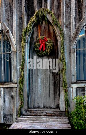 Beautiful door is decorated for Christmas with an evergreen wreath ...