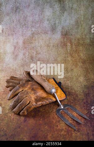 Still life of a pair of leather gardening gloves and a hand fork. Stock Photo