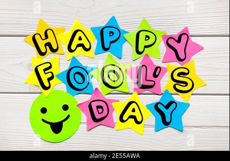 Happy Fool's Day text on colorful sticky notes in the shape of a star on a light wood background. Stock Photo