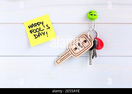 Key ring hung on the wall with a car key made of cardboard as a joke for the celebration of Fool's Day. Space for text. Stock Photo