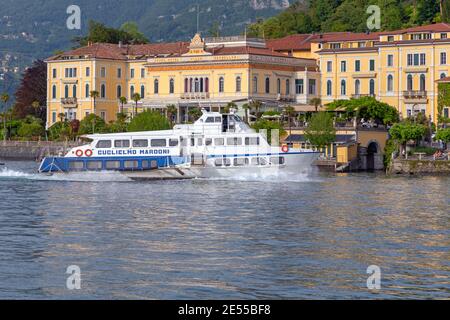 Bellagio, Italy - June 14, 2019: Hydrofoil Ship in Front of Houses at Lake Como in Bellagio, Italy. Stock Photo