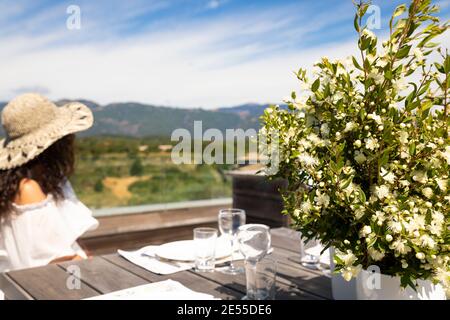Woman in outdoor roof table set for lunch with view and flower Stock Photo
