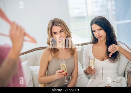 Three beautiful girls choosing a dress and looking unsatisfied Stock Photo