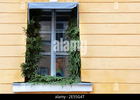 The window in the building is yellow, it is decorated with fir branches for Christmas. High quality photo Stock Photo