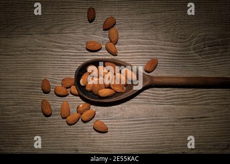 Almonds on a wooden spoon on a wooden surface. Stock Photo