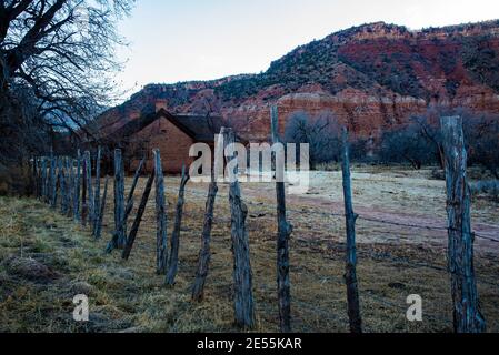 Old pioneer home nestles below the red rock mesa of southern Utah, USA.  This pioneer home remains in the ghost town of Grafton, Utah, USA. Stock Photo