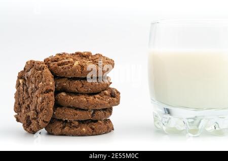 Stack of homemade sweet chocolate cookies with glass of milk on white background. Stock Photo