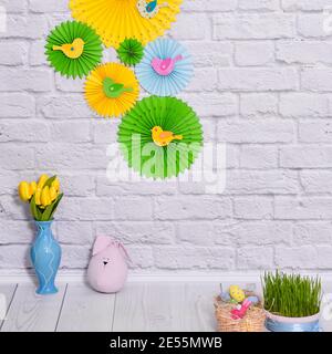 Easter composition with Easter eggs, a bouquet of flowers, live green grass on a white brick background.  Stock Photo