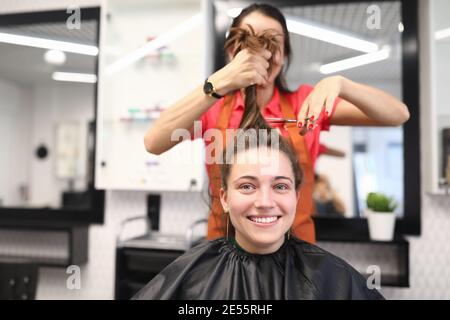 Portrait of smiling woman in hairdressing salon, which master cuts her hair Stock Photo