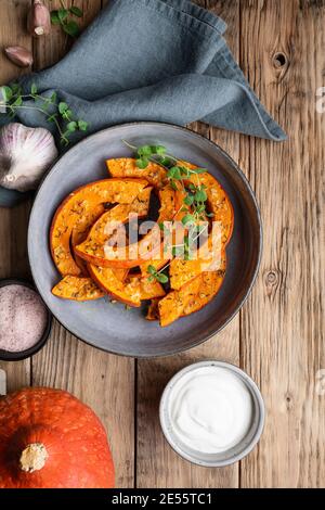 Easy roasted Hokkaido pumpkin slices topped with olive oil, grated garlic and herbs, served with sour cream Stock Photo