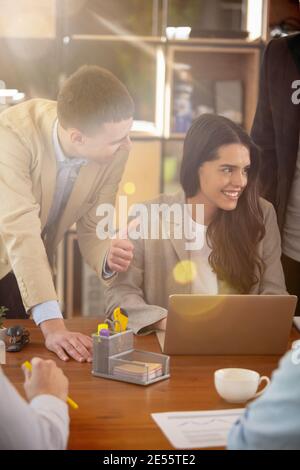 Deciding. Front view colleagues working together in a office using modern devices during creative meeting. Smiling girl discussing manager. Concept of business, office, finance, open space. Stock Photo