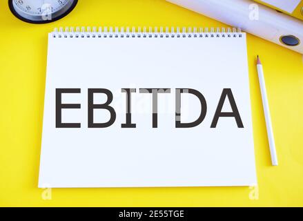 Conceptual hand writing showing Ebitda. Business photo text Earnings before tax is measured to evaluate company performance written in Notebook on yel Stock Photo