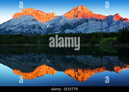 Golden sunrise reflecting off the calm waters of Wedge Pond beneath Mount Kidd in the Kananaskis Country of the Canadian Rockies near Banff National P Stock Photo