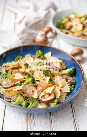 Mushroom pasta salad with steamed broccoli and baked chicken meat slices for lunch Stock Photo