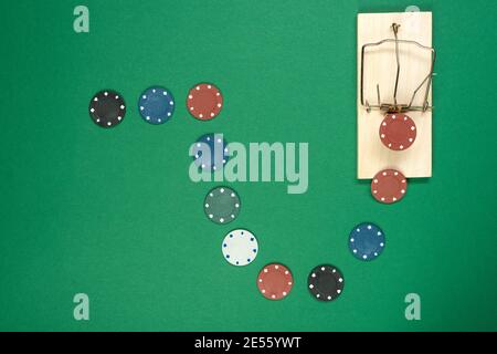 Colorful casino chips leading to mousetrap on green background, game trap. Stock Photo