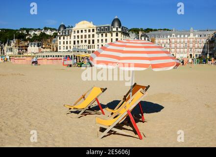 Beach wooden chaise lounge and umbrella with fringe. Trouville-sur-Mer (Normandy, France). Stock Photo