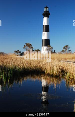 The towering Bodie Island Lighthouse, on the Outer Banks of North Carolina, is reflected in the nearby marsh Stock Photo