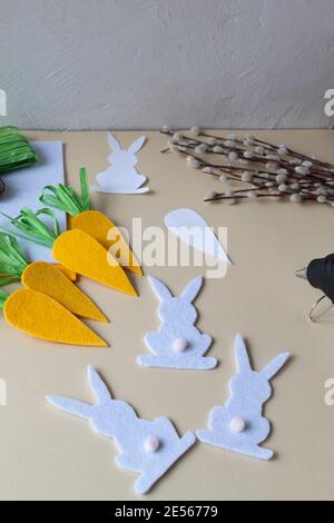 How to make an Easter garland of rabbits and carrots with your own hands from felt. Step by step instruction. Step 9. Glue the tails to the felt bunni Stock Photo