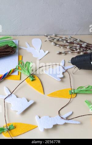 How to make an Easter garland of rabbits and carrots with your own hands from felt. Step by step instruction. Step 10. We put all the elements on a br Stock Photo