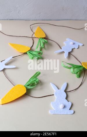 How to make an Easter garland of rabbits and carrots with your own hands from felt. Step by step instruction. Finished garland. Stock Photo