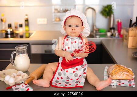 Cute little baby girl in a cook cap in home kitchen Stock Photo