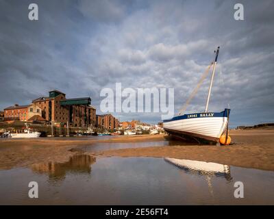 Wooden rowing boat on the sand banks of Wells harbour. Stock Photo