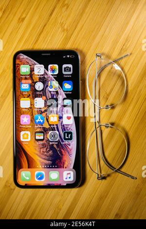 Paris, France - Oct 02, 2018: New latest iPhone smartphone telephone on the wooden table bamboo background with luxury titanium spectacle eyewear places near Stock Photo