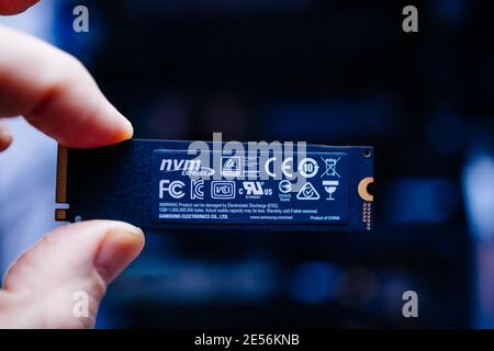 London, United Kingdom - Jan 18, 2019: POV personal perspective male hand holds new M2 connector the new Samsung NVME V-Nand SSD Samsung 970 disk with one terabyte storage space - blue background and signage Product of China Stock Photo