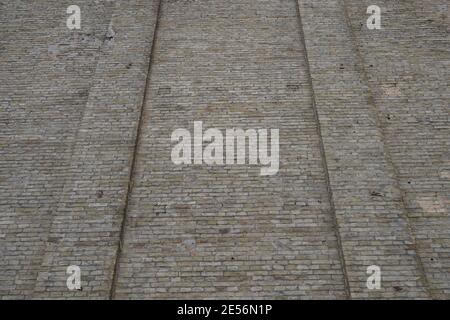 Old brick wall with defects and cracks in perspective Stock Photo