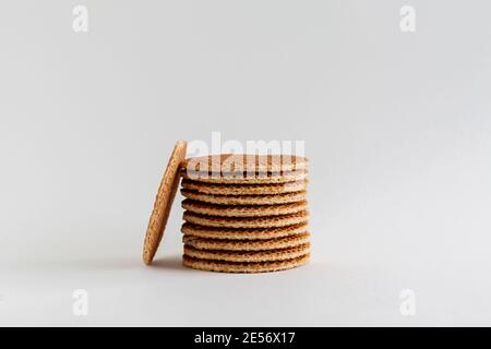 A stack of Dutch stroopwafels (syrup or caramel waffles) with one cookie in the side on a white background, close up Stock Photo